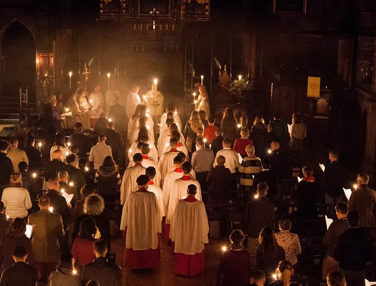 Clergy & choir processing to altar during Easter Vigil mass & lighting candles on way.