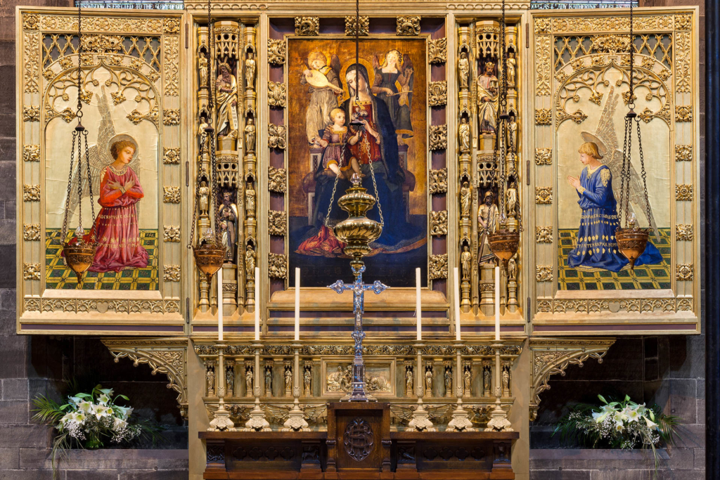 Reredos (triptych screen behind altar) designed by Hay & Henderson and featuring a copy of Virgin and Child with Saints by Benvenuto di Giovanni, with candles for mass.