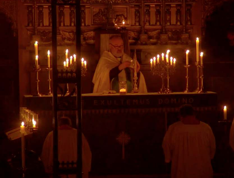 Father John ministering at the altar by the candlelight